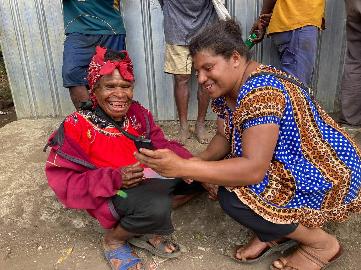 Two women smiling with joy with an audio Enga New Testament.